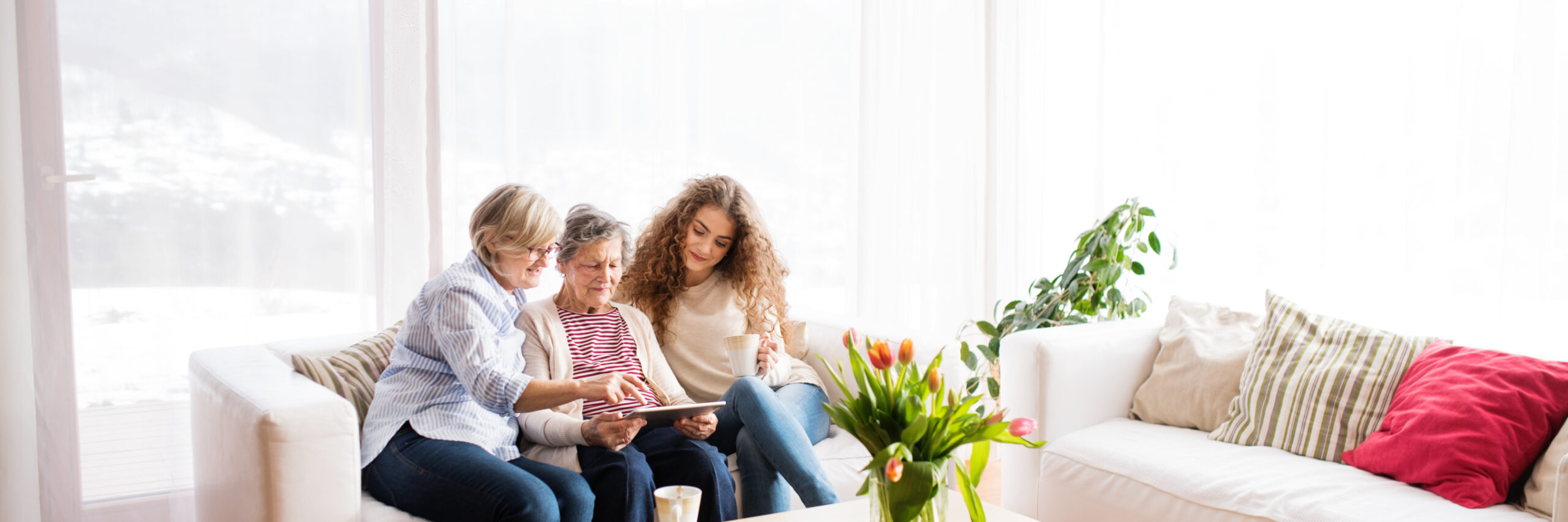 A teenage girl, mother and grandmother with tablet at home.
